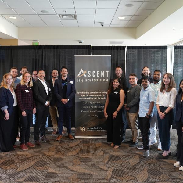 A large group of diverse people pose next to a promotional banner