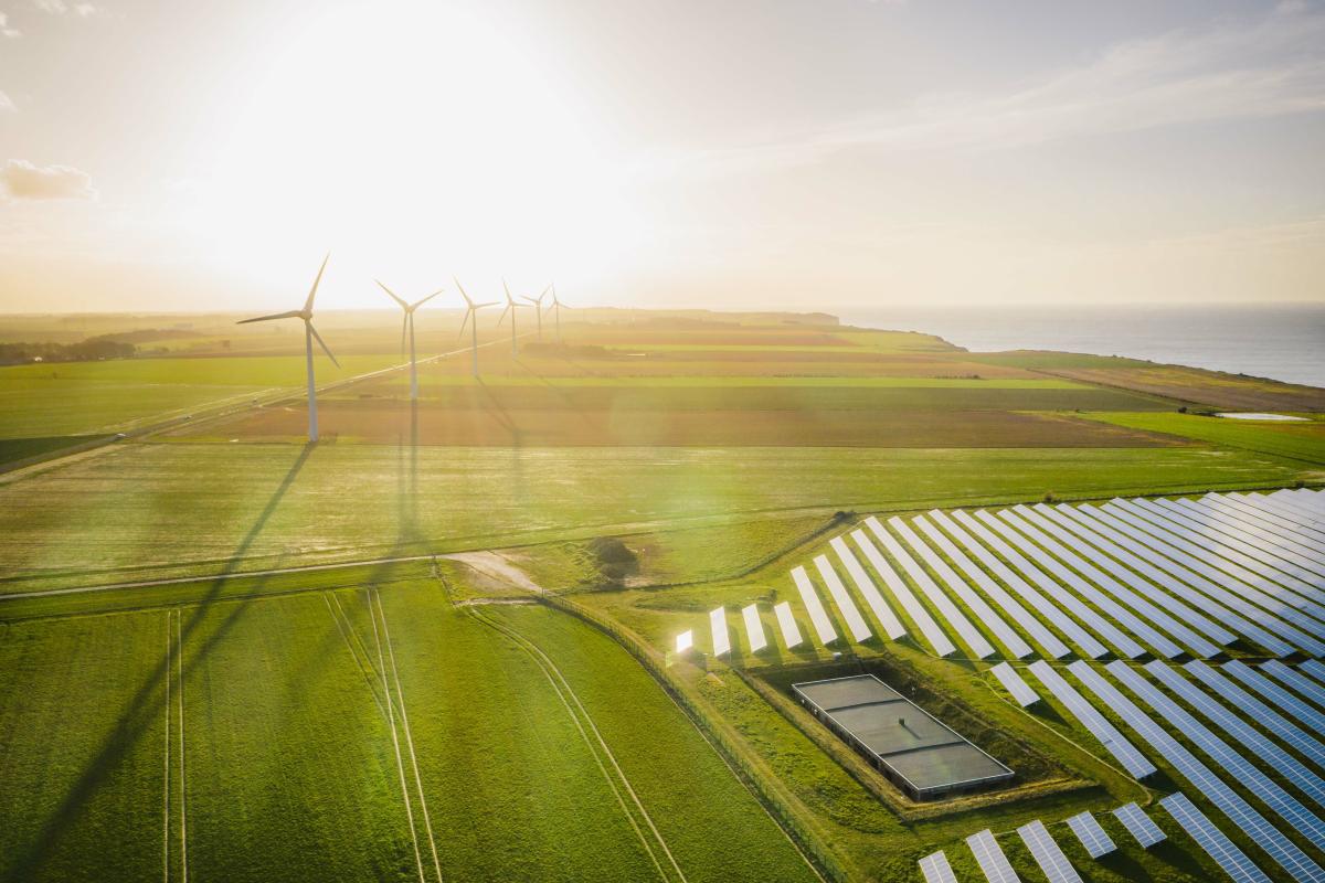 Sunset over farm land covered in windmills and solar arrays.