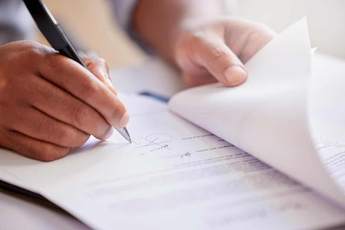 Close up on a pair of hands signing paperwork