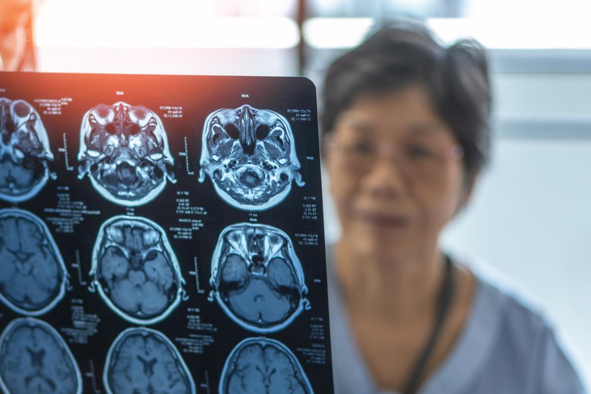 An older woman and a doctor examine brain scans