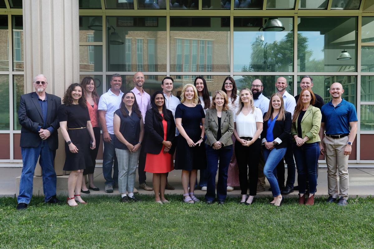 A diverse group of people in business clothes pose for a photo on a sunny day