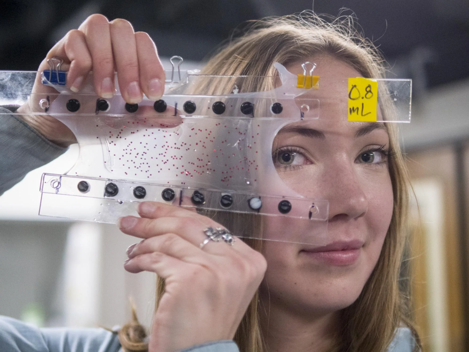 Researcher looks at the camera through a plastic device