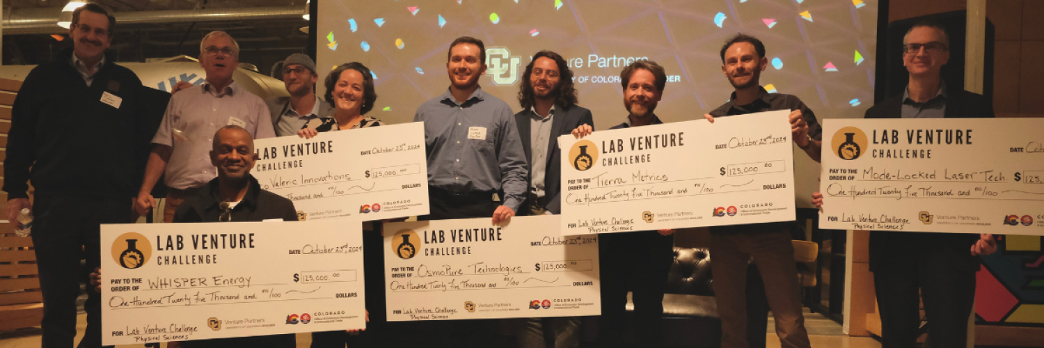 A diverse group of people stand with giant prize checks.