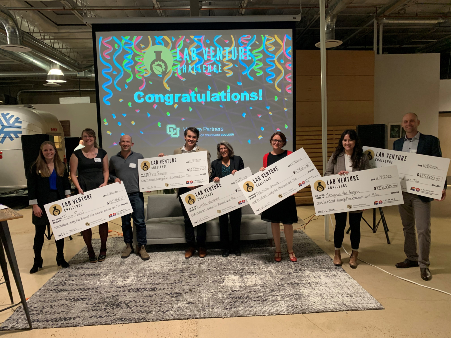 Winners hold up their large prize checks