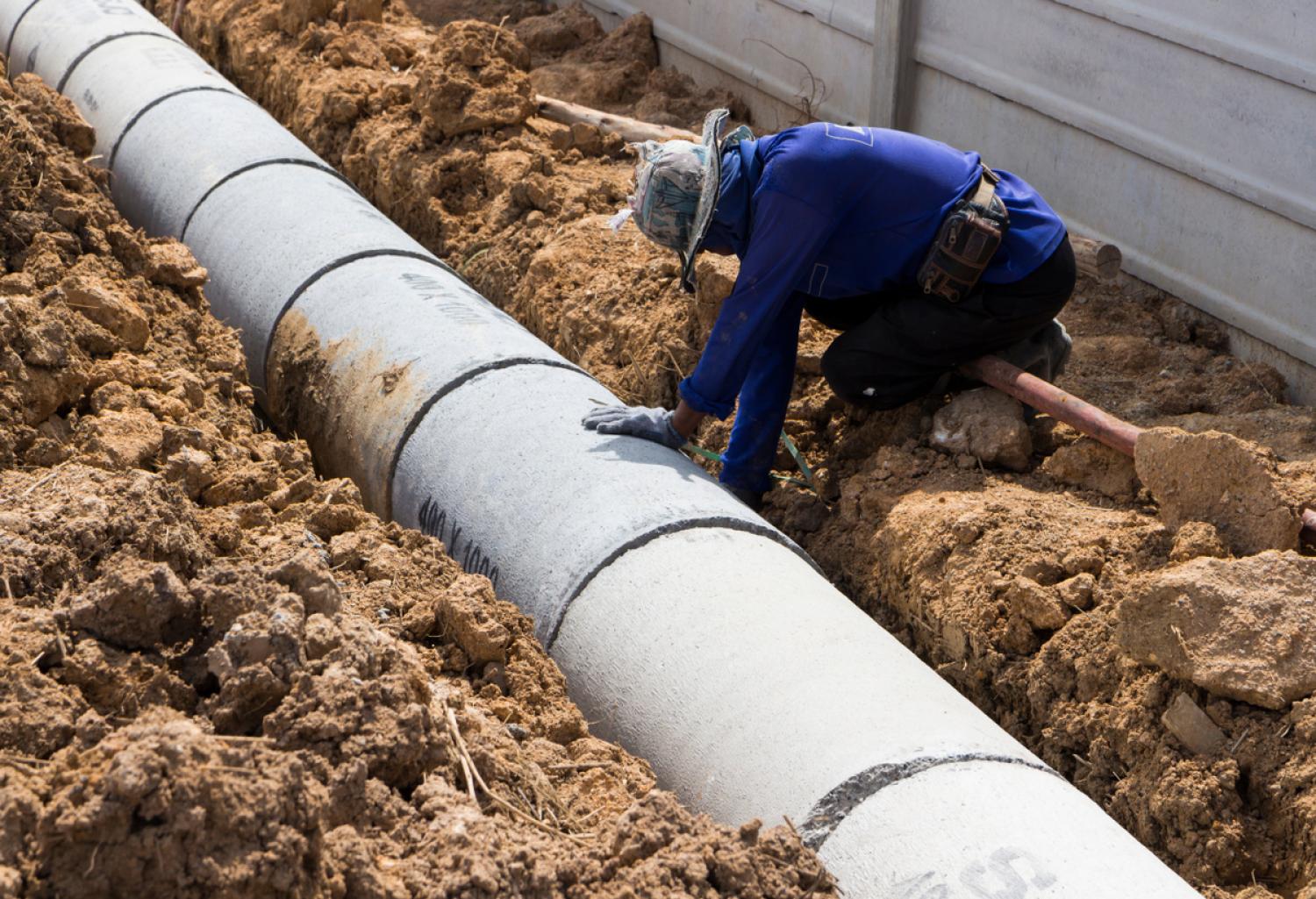 Worker laying pipe in a trench