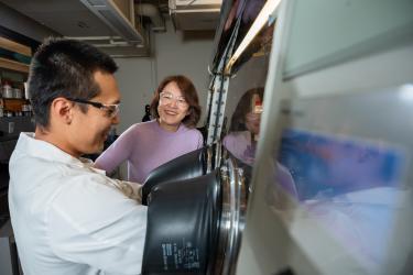 A man and a woman laugh while working together to in a laboratory