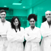 A diverse group of people wearing lab coats poses for a photo