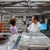 Two researchers, a woman and a man, examine a small device he holds up in a laboratory.