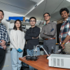 A group of engineers stands behind their mechanical invention