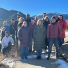 A group of people wearing winter clothes pose for a picture in the mountains