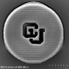 A microscopic image of the University of Colorado logo on a circular disc