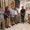 CU Physics Professor Ivan Smalyukh standing with his research team in a laboratory setting, surrounded by scientific equipment and materials. The group is smiling and posed together, highlighting their collaboration and achievement in material science.
