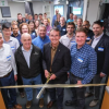 A group of predominantly white men stand at a ribbon cutting in the entrance of a laboratory