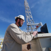 Engineer works at computer next to monitoring tower