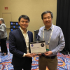 Two scientests stands with an awards plaque