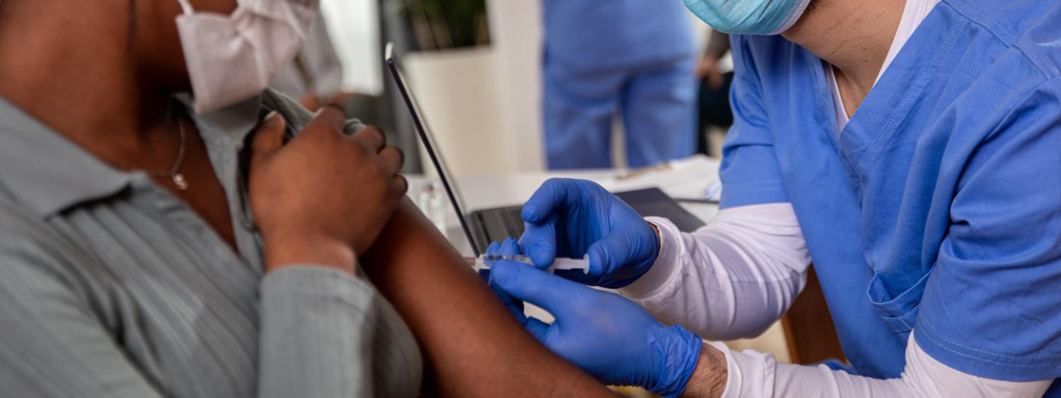 A man gives a young woman a vaccine shot in the arm