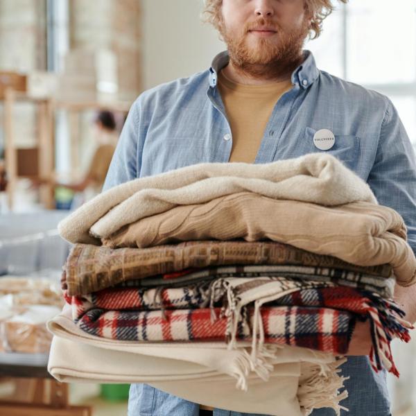 volunteer holding a stack of blankets facing the camera