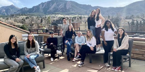 A group of students posing some sitting and standing in front of the flatiron mountains facing west