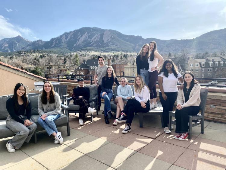 A group of students posing some sitting and standing in front of the flatiron mountains facing west. 