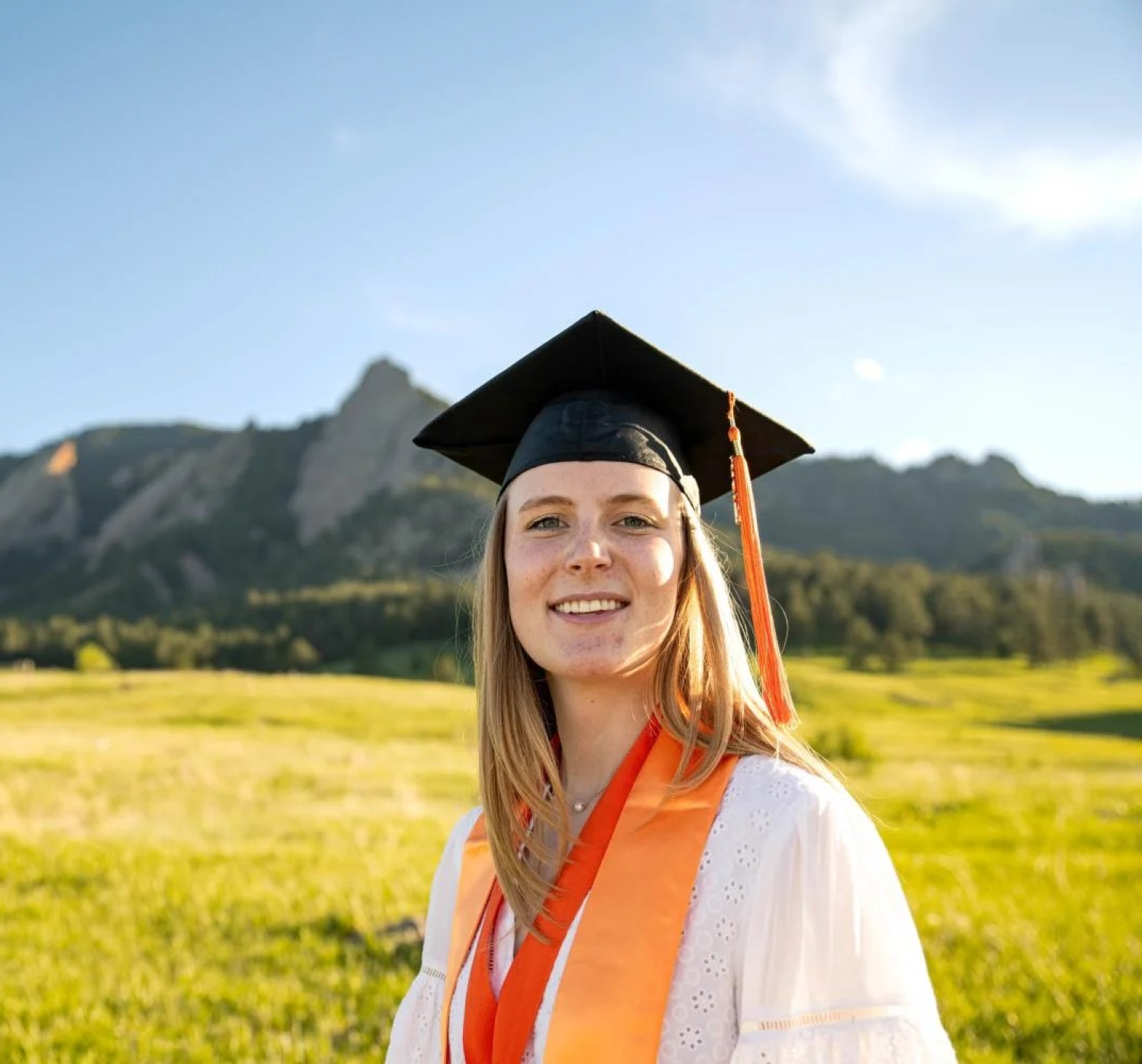 Woman in graduation cap stands in front of mountains