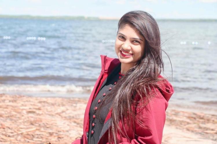 Woman in pink jacket smiles at the beach