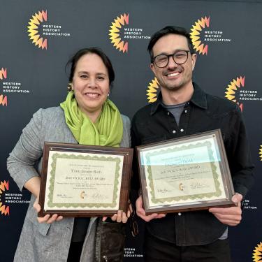 Professors smiling with certificates at award ceremony.