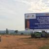 Feminist Lens on Global China Flyer, Chinese billboard of Uganda Free-Trade Zone Policy with person walking and mountains in the background as seen on Dr. Wyrod's research trip.