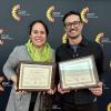 Professors smiling with certificates at award ceremony.